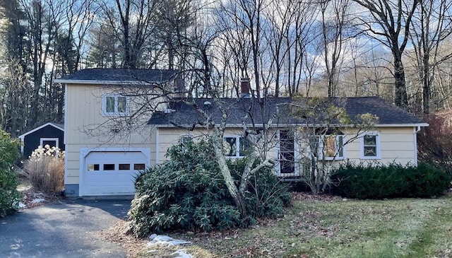 view of front of house featuring aphalt driveway, a chimney, and a garage