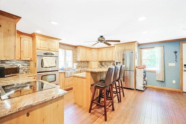 252 Howe St, East Brookfield, MA 01515 - kitchen featuring appliances with stainless steel finishes, light brown cabinetry, a sink, a breakfast bar, and recessed lighting