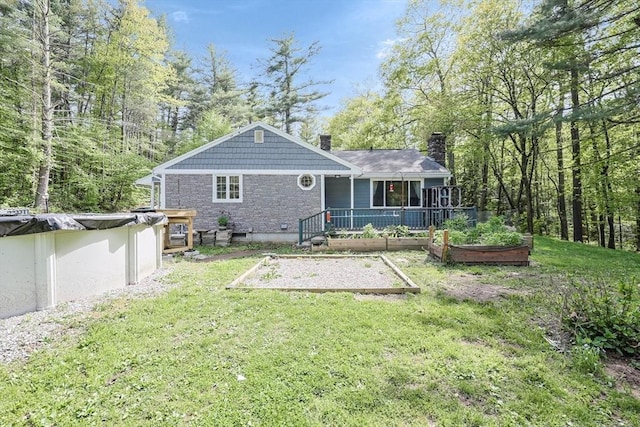 252 Howe St, East Brookfield, MA 01515 - back of house with a vegetable garden, a chimney, a lawn, a covered pool, and stone siding