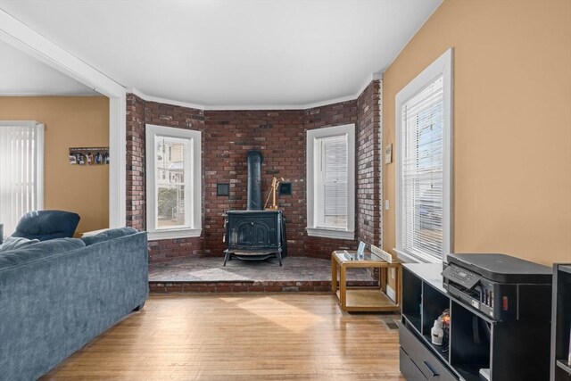 living room featuring a wood stove, brick wall, and wood finished floors