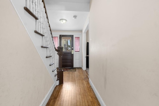 corridor featuring hardwood / wood-style flooring, stairs, and baseboards