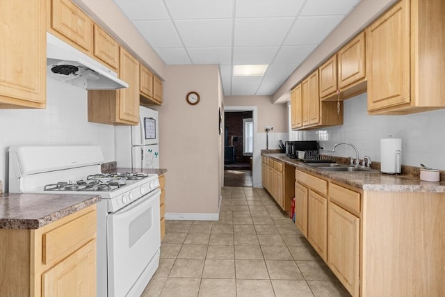 kitchen featuring under cabinet range hood, white range with gas cooktop, a sink, and light brown cabinetry