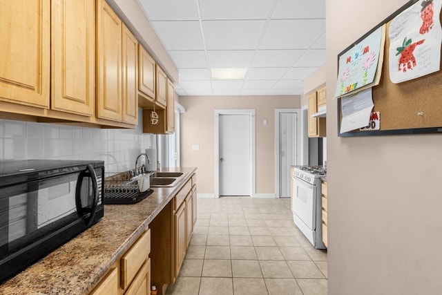 kitchen featuring gas range gas stove, a paneled ceiling, decorative backsplash, light tile patterned flooring, and black microwave