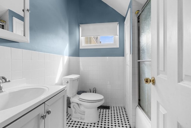 full bathroom with toilet, vanity, tile walls, wainscoting, and tile patterned floors