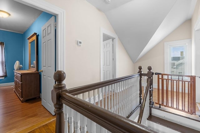 hallway featuring lofted ceiling, wood finished floors, an upstairs landing, and baseboards