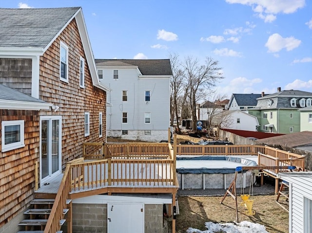 rear view of property featuring a fenced in pool, a residential view, and a deck