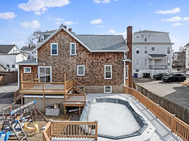 back of house with a chimney, a shingled roof, fence, a wooden deck, and stairs