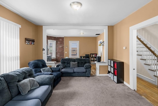 carpeted living area featuring stairs and baseboards