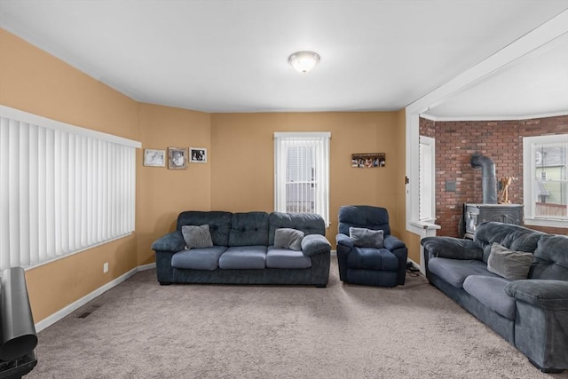 living room featuring a wood stove, baseboards, and carpet flooring