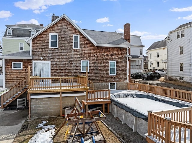 rear view of property featuring a deck, roof with shingles, a chimney, and fence