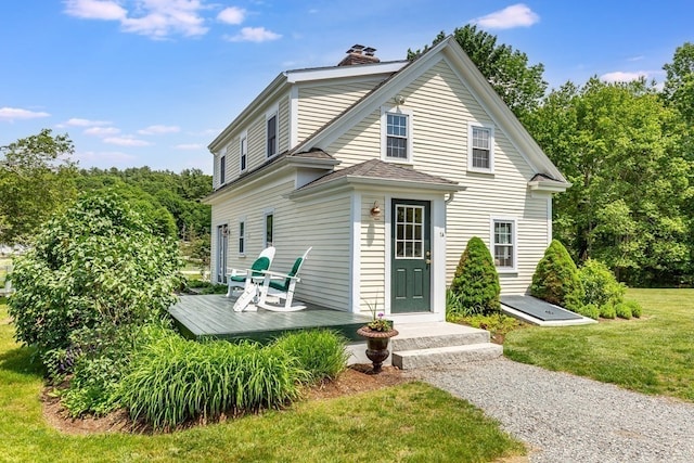 back of property with a deck and a lawn