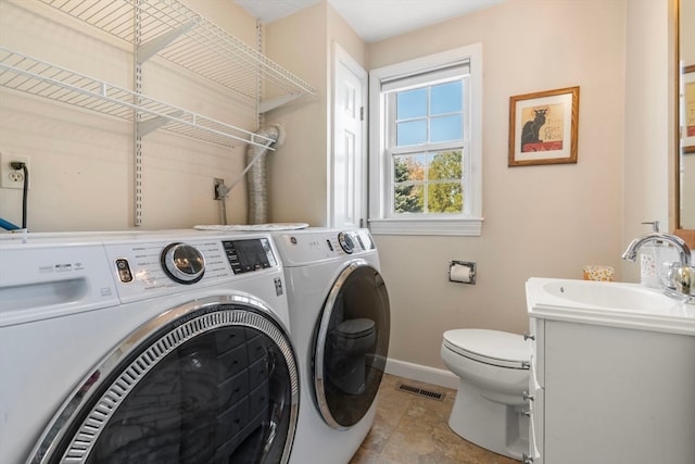 clothes washing area featuring light tile patterned flooring, washer and dryer, and sink