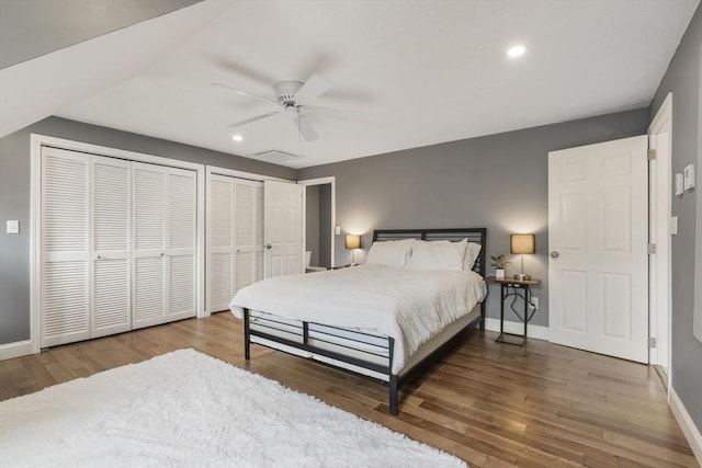 bedroom featuring recessed lighting, wood finished floors, multiple closets, ceiling fan, and baseboards
