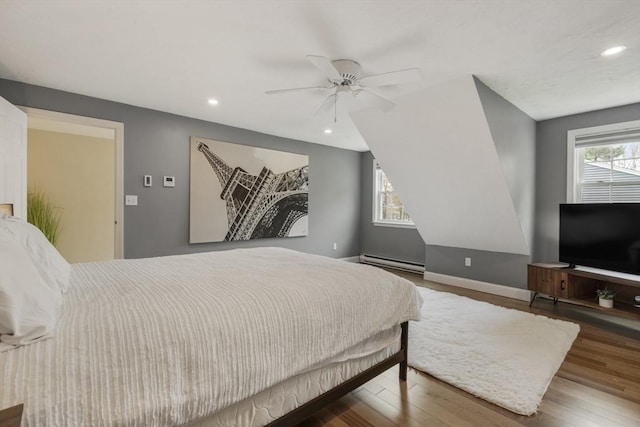 bedroom with a baseboard heating unit, recessed lighting, wood finished floors, and baseboards