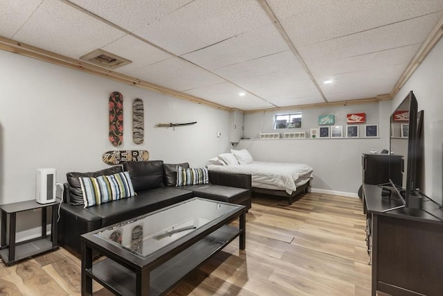living room featuring a paneled ceiling, visible vents, baseboards, and light wood-style floors