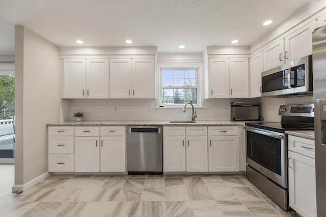 kitchen featuring backsplash, a sink, white cabinets, and appliances with stainless steel finishes