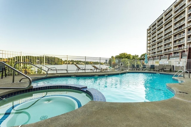 view of pool featuring a patio area, fence, and a pool with connected hot tub