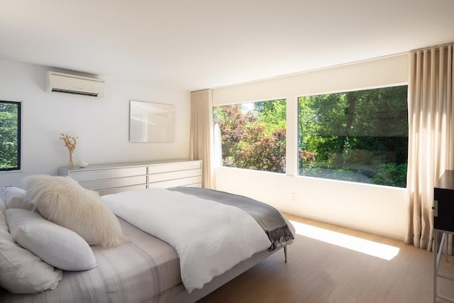 bedroom with a wall unit AC and wood finished floors