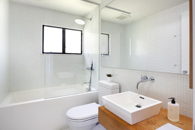 full bathroom featuring shower / tub combination, toilet, tile walls, and a sink