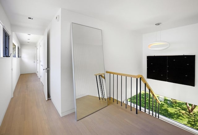 hallway with an upstairs landing and light wood-type flooring