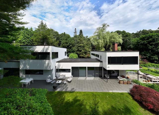 rear view of house with a lawn, a patio, and a sunroom