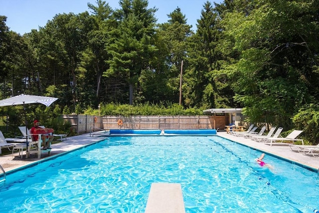 community pool featuring a patio area, a diving board, and fence