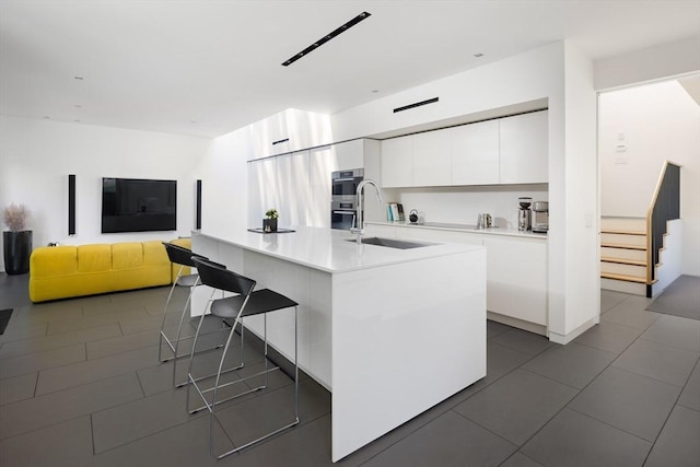 kitchen featuring white cabinets, modern cabinets, a breakfast bar area, and a sink