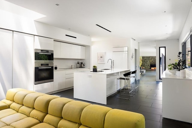 kitchen with modern cabinets, refrigerator, open floor plan, white cabinets, and light countertops