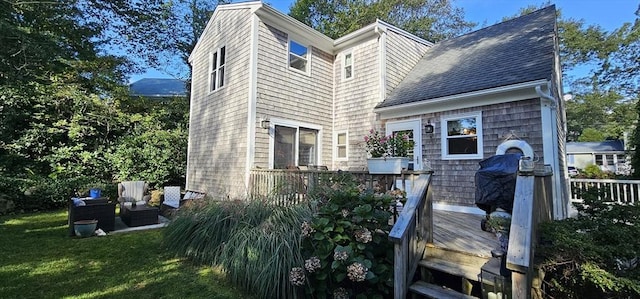 back of property featuring a wooden deck, an outdoor hangout area, and a lawn