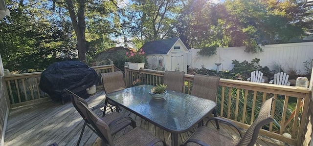 wooden deck featuring area for grilling and a storage unit