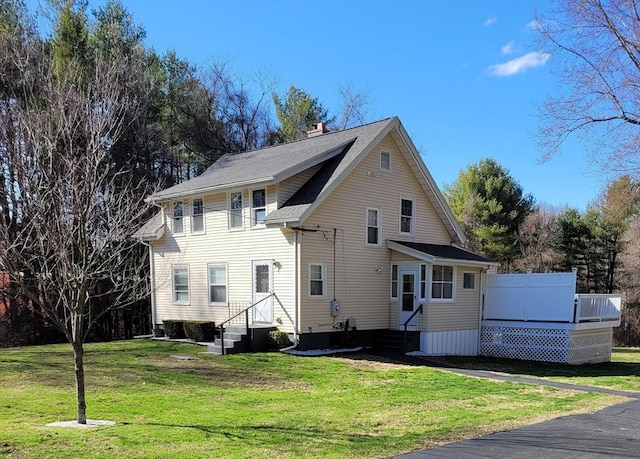 exterior space featuring entry steps, a lawn, and a chimney