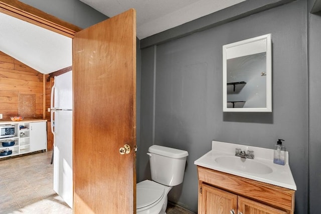 bathroom featuring toilet, wooden walls, lofted ceiling, and vanity