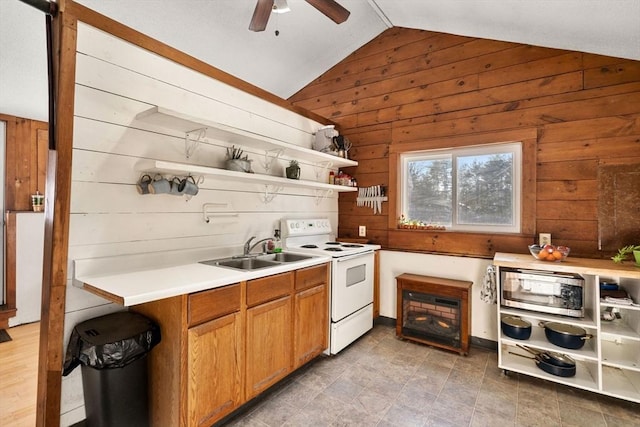 kitchen featuring ceiling fan, white range with electric cooktop, sink, vaulted ceiling, and wood walls