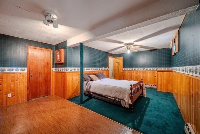 12 Jensen Ave, Chelmsford, MA 01824 - bedroom with a baseboard heating unit, baseboard heating, a wainscoted wall, wood walls, and wood finished floors