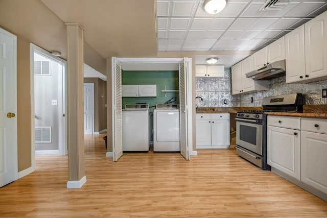 998 Wood, Swansea, MA 02777 - kitchen featuring stainless steel gas range oven, under cabinet range hood, washing machine and dryer, dark countertops, and white cabinetry