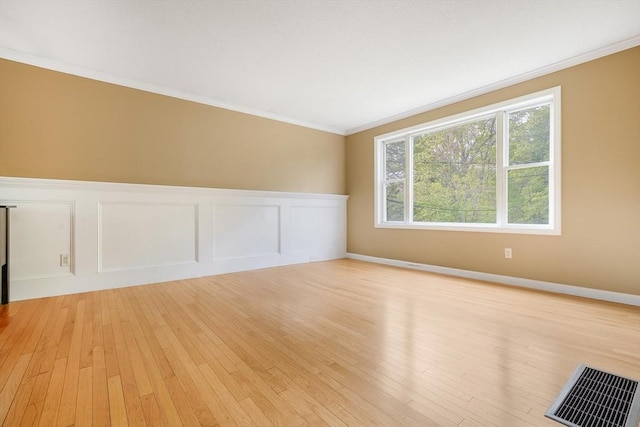 998 Wood, Swansea, MA 02777 - empty room featuring crown molding, light wood-style flooring, a wainscoted wall, and a decorative wall