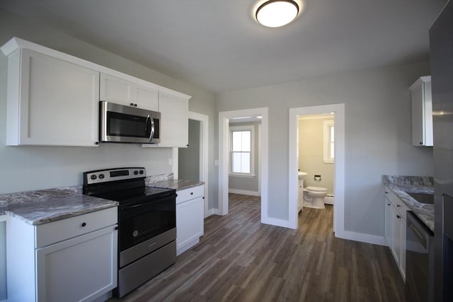 kitchen with light stone counters, dark wood-style floors, white cabinetry, appliances with stainless steel finishes, and baseboards