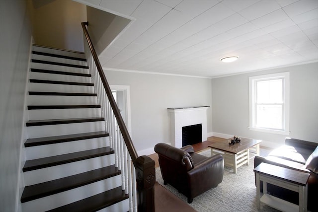 living area with ornamental molding, wood finished floors, stairway, a fireplace, and baseboards