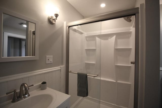 full bathroom with vanity, a stall shower, and wainscoting