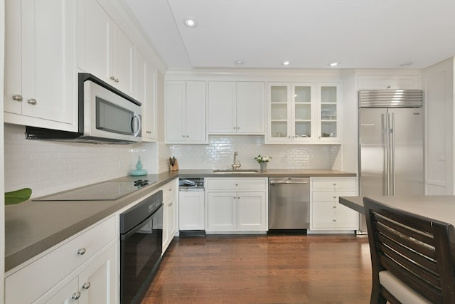 kitchen featuring white cabinetry, backsplash, black appliances, dark hardwood / wood-style floors, and sink