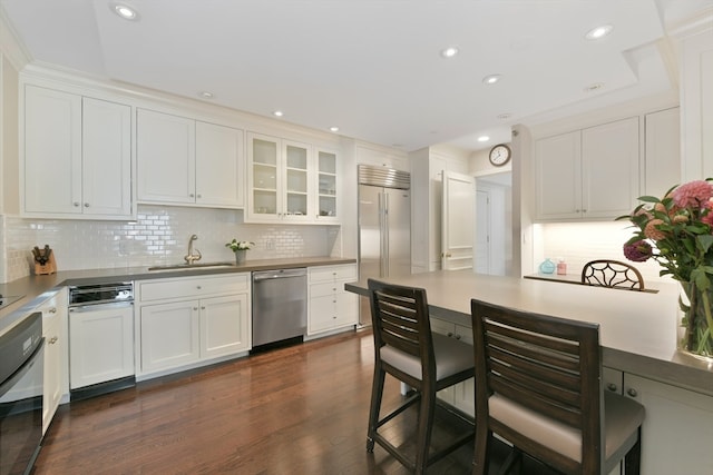 kitchen with backsplash, white cabinetry, appliances with stainless steel finishes, and dark hardwood / wood-style flooring