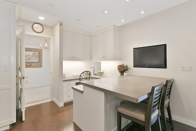 kitchen with kitchen peninsula, tasteful backsplash, white cabinetry, a kitchen breakfast bar, and dark hardwood / wood-style flooring