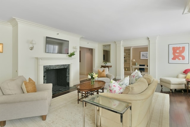 living room with ornamental molding, wood-type flooring, decorative columns, and a fireplace