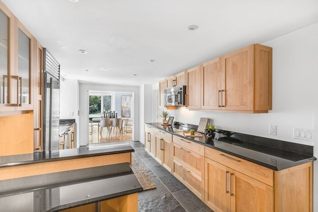 kitchen featuring light brown cabinetry, dark tile patterned flooring, and stainless steel appliances