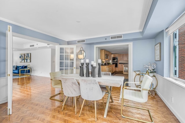 dining space with parquet floors and a raised ceiling