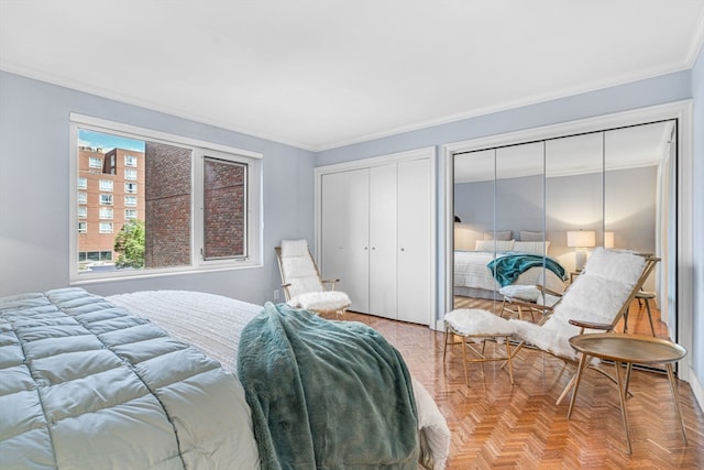 bedroom featuring ornamental molding, two closets, and light parquet flooring