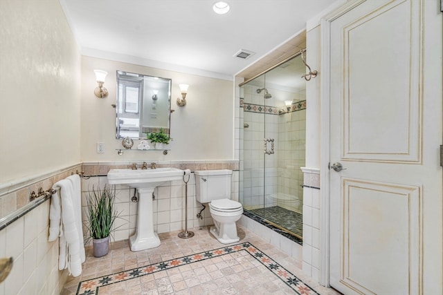 bathroom with toilet, a shower with door, tile patterned flooring, and tile walls