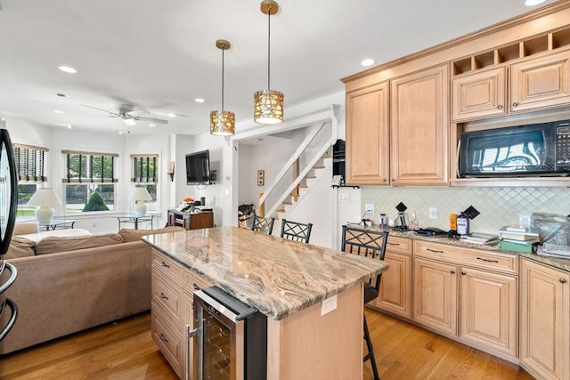 379 Hunnewell St, Needham, MA 02494 - kitchen featuring beverage cooler, black microwave, open floor plan, decorative backsplash, and light wood-type flooring