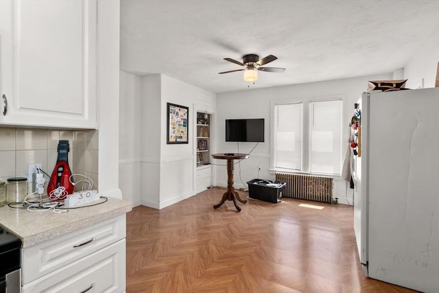 379 Hunnewell St, Needham, MA 02494 - kitchen with radiator heating unit, freestanding refrigerator, light countertops, ceiling fan, and white cabinets