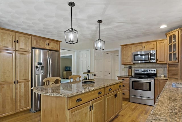 22 Mikayla Ann Dr, Rehoboth, MA 02769 - kitchen featuring stainless steel appliances, a center island, light stone countertops, glass insert cabinets, and light wood-type flooring